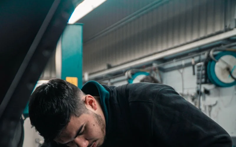 Mechanic working under the hood in an auto repair shop