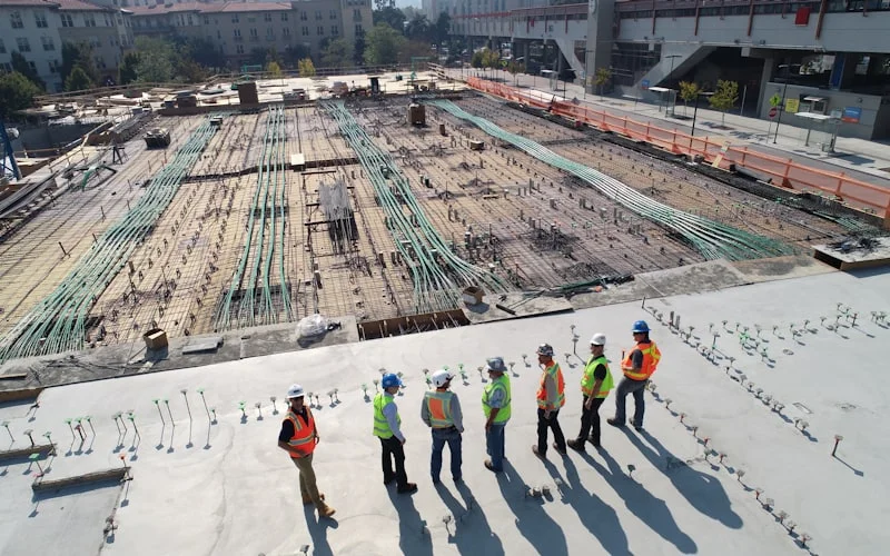 Construction crew in safety vests reviewing a concrete job site
